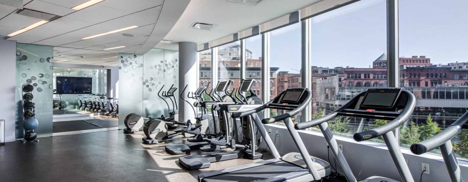 Fitness center with elliptical looking out into a city view