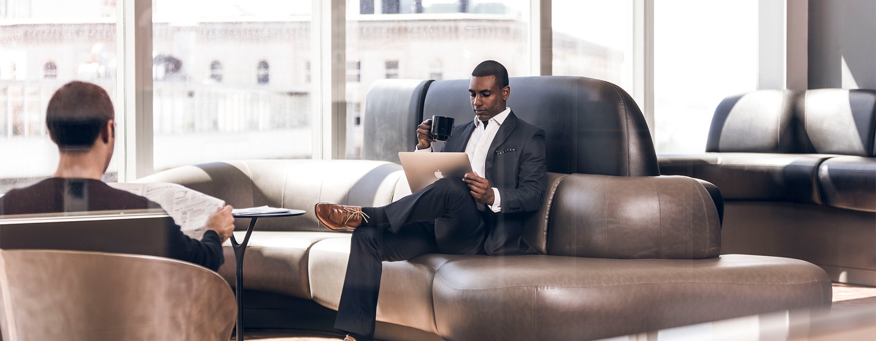 Man sitting on couch with laptop and drinking coffee
